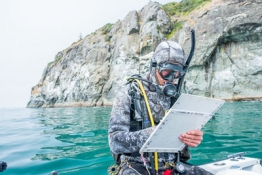 scuba diver getting ready to go in the water writing on a clipboard
