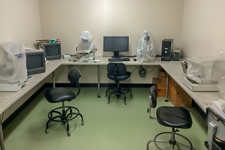 small room with a table around the edge of the room and computers and microscopes